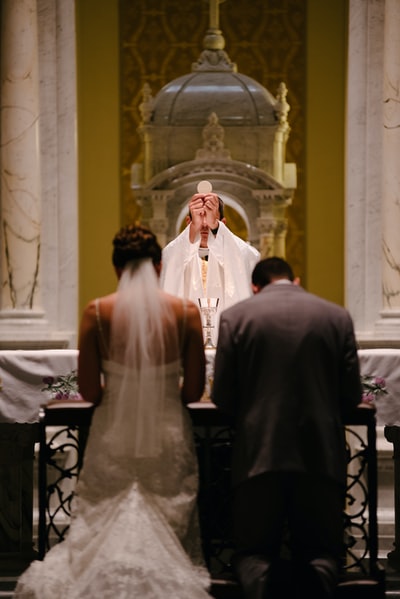 新郎和新娘在神父面前跪提高圣体
